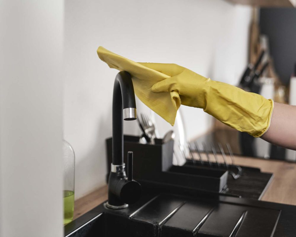 Close up of caucasian woman cleaning tap in kitchen at home